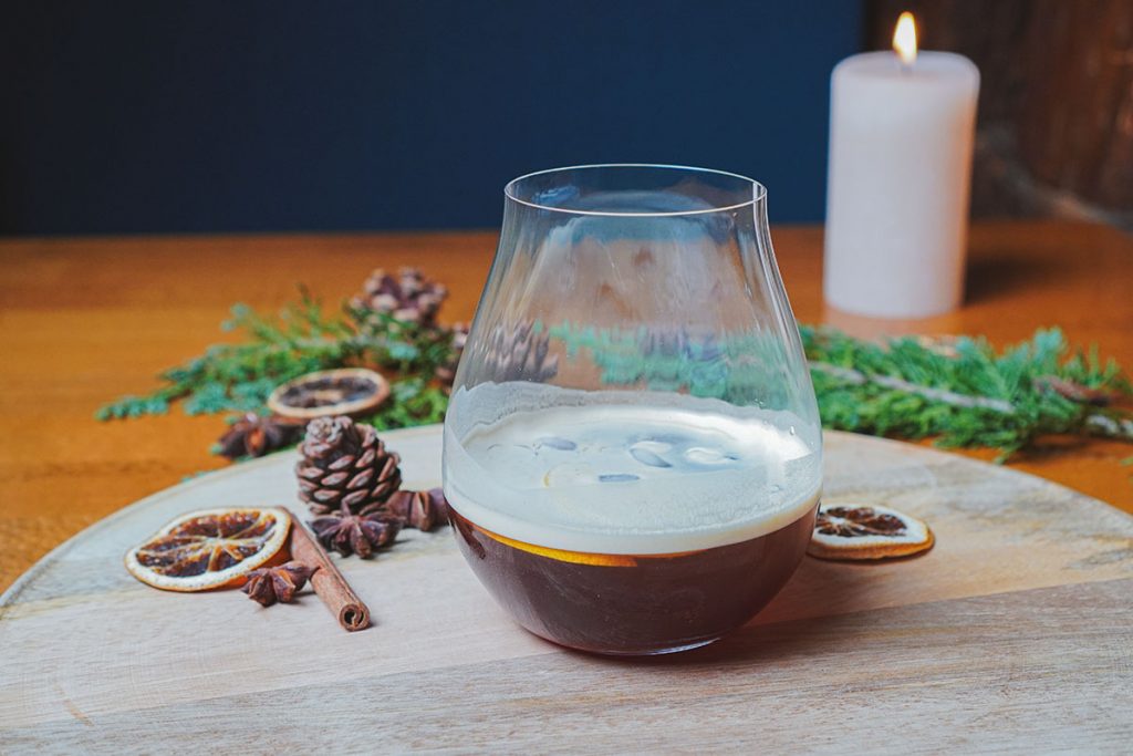 Chilled Gin steht in einem bauchigen Glas auf einem Holz-Tablett, rundherum liegt winterliche Dekoration