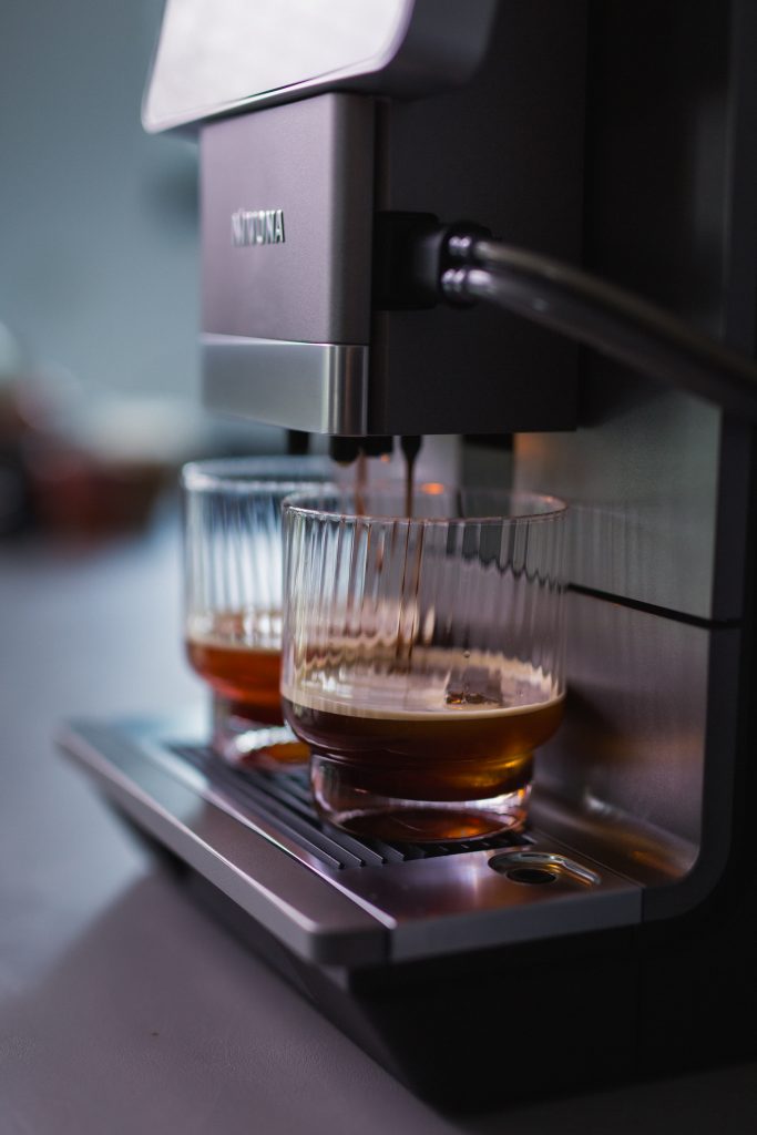 Frisch zubereiteter Chilled Kaffee steht in zwei Gläsern auf dem Tropfblech des Kaffeevollautomaten NIVO 9101